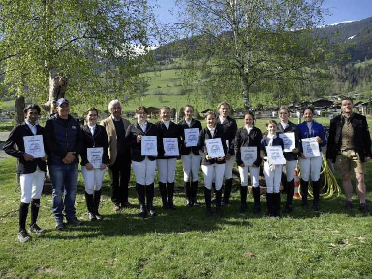 Elf ReiterInnen mit Urkunden posieren nach Reiterpass- und Reiternadelprüfung im Grünen